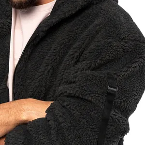 Close-up detail showing the soft texture of a black fuzzy sherpa fleece jacket with strap