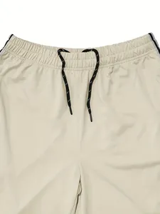 Close-up of elastic waistband with black and white drawstring on beige sports pants