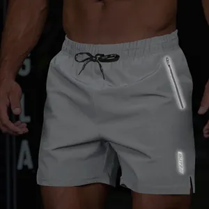 Detailed view of grey men's fitness shorts with reflective zipper and logo design