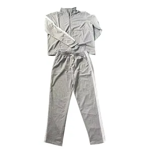 Detail of grey men's tracksuit set featuring white side stripes and zip-up jacket.