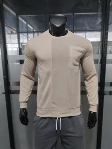 Close-up of beige men's sweatshirt featuring corduroy patchwork and a chest pocket detail