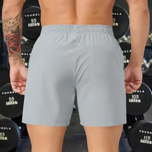 Back view of men's grey loose-fit athletic shorts presented in a fitness gym setting