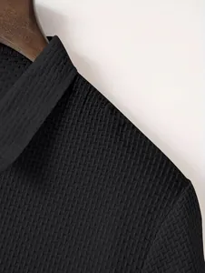 Detailed macro view of the black textured waffle-knit fabric on a men's casual Polo shirt