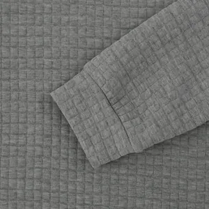 Detailaufnahme des grauen Waffelstrick-Stoffes und der Rippbündchen eines Herren-Sweatshirts