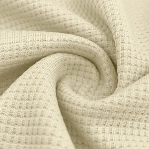 Macro close-up shot of premium cream-colored waffle knit fabric texture for men's polo shirt