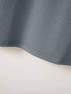 Detail shot of heavy grey waffle texture fabric and hem of a men's casual polo shirt