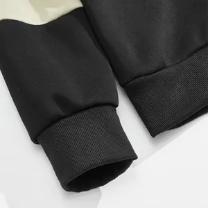 Detailed view of the ribbed cuffs and hem on a two-tone black and cream men's sweatshirt