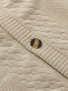 Close-up of beige men's cardigan showing jacquard texture and brown marbled button detail