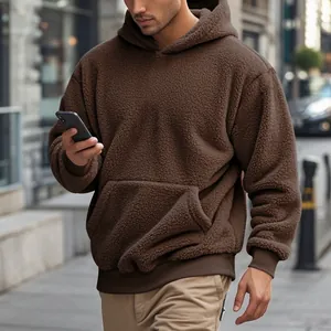 Close-up detail of men's brown oversized teddy fleece hoodie in a stylish street setting