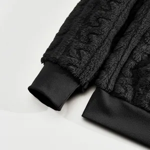 Close-up detail of black jacquard fleece hoodie showing ribbed cuffs and soft texture