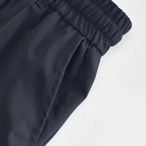 Vista dettagliata dell'elastico in vita e della tasca laterale dei pantaloni sportivi blu