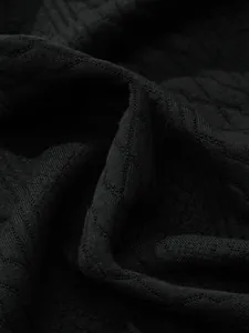 Close-up detail of black jacquard knit fabric showing diamond pattern texture