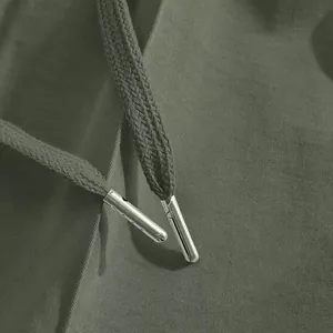 Dettaglio di pantaloni sportivi oliva con punte in metallo del cordino di qualità