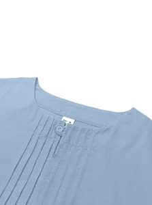 Close-up shot of light blue linen shirt neckline featuring button and pleated details