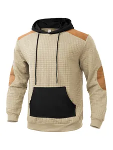 Detailed close-up of khaki quilted hoodie with black pocket and brown elbow patches