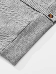 Detail shot showing the grey jacquard texture and button of a men's vintage cardigan.
