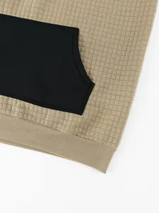 Close-up detail of a waffle knit hoodie featuring a black kangaroo pocket and ribbed hem