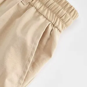Dettaglio ravvicinato della fascia elastica e della tasca laterale dei pantaloni beige