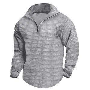 Détail rapproché du tissu jacquard gaufré gris sur un sweat-shirt à demi-zip pour homme.