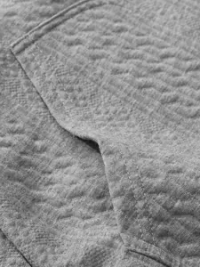 Close-up detail of grey jacquard fabric and pocket stitching on men's retro cardigan