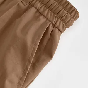 Dettaglio dei pantaloni sportivi marroni da uomo con vita elastica e tasca laterale