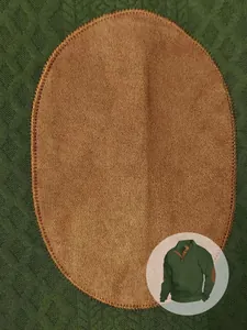 Dettaglio della toppa marrone sui gomiti in pelle scamosciata su maglia verde