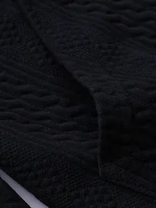 Macro detail of black jacquard knit fabric showing intricate vintage diamond patterns