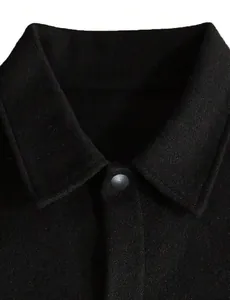 Nahaufnahme des klassischen Umlegekragens und Druckknopfs an einer schwarzen Wolljacke für Herren