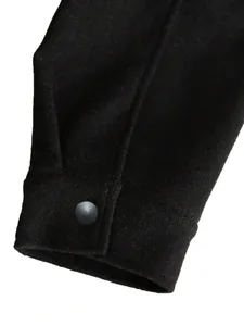 Detailansicht des Ärmelbündchens einer schwarzen Wolljacke mit mattem Druckknopf