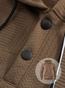 Gros plan d'un sweat à capuche jacquard marron montrant les boutons et la texture