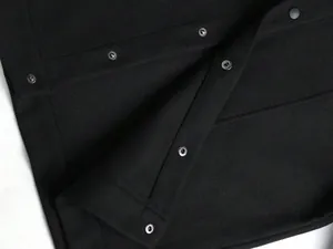 Detailaufnahme der schwarzen Wollmischjacke für Herren mit robustem Druckknopfverschluss