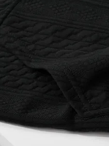 Macro detail of men's black knit cardigan showing textured diamond jacquard pattern