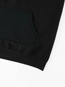 Detailed macro view of black waffle texture fabric and kangaroo pocket on men's casual hoodie