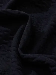 Macro detail of navy blue jacquard knit fabric showing intricate geometric texture patterns