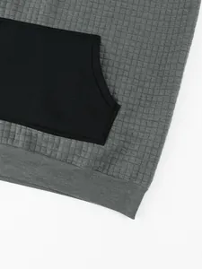 Close-up of grey men's hoodie detail showing waffle knit texture and black kangaroo pocket