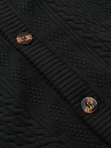 Close-up of black textured knit cardigan with marble buttons and jacquard patterns