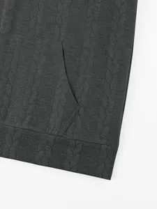 Close-up of dark charcoal heavy jacquard hoodie with cable knit texture and kangaroo pocket.