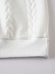Primo piano di una felpa bianca pesante con maglia jacquard a rombi e orlo a costine