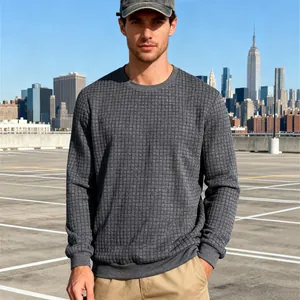 Detailansicht eines grauen Herren-Sweatshirts mit Jacquard-Karomuster in urbaner Umgebung.