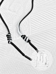 Gros plan sur le tissu jacquard et les cordons de serrage tressés d'un sweat à capuche blanc.