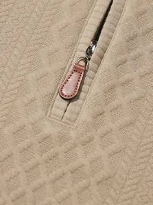 Macro detail of high-quality jacquard fabric and leather zipper puller on beige sweatshirt