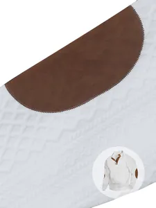 Dettaglio del tessuto a maglia jacquard bianco e toppa marrone sul gomito di un maglione da uomo.