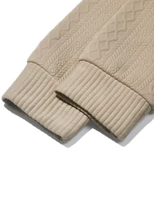 Macro detail shot of beige jacquard knit fabric and ribbed cuffs on men's sweatshirt.
