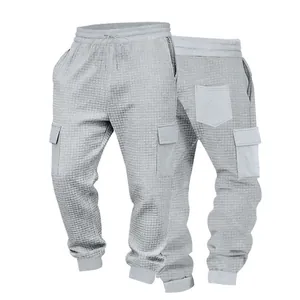 Vista dettagliata della trama jacquard grigia sui pantaloni jogger cargo da uomo.