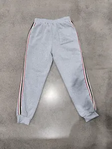 Pantaloni sportivi grigi da uomo con strisce laterali rosse e nere, vita ed orlo elastici.