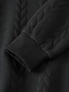 Primo piano di una pesante felpa nera in jacquard con dettaglio del polsino a coste