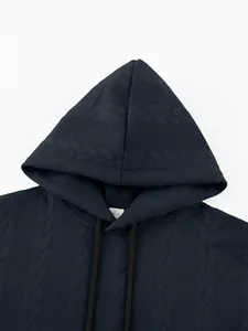Macro view showing the thick jacquard cable-knit texture of the dark navy hooded sweatshirt