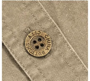 Gros plan sur un bouton gravé vintage sur le tissu sergé kaki d'une chemise de travail