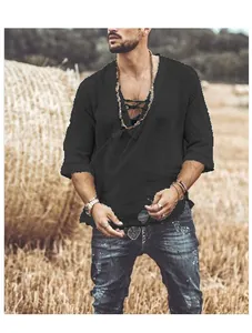 Close-up of a men's black cotton linen lace-up top against a rustic hay bale background