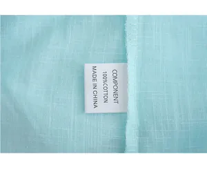 Close-up detail of 100% cotton wash label and fabric texture of a mint green shirt